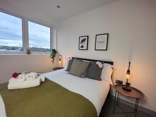 a bedroom with a bed and two tables and two windows at Pass the Keys Newly Built Modern Central Apartment in Wolverhampton