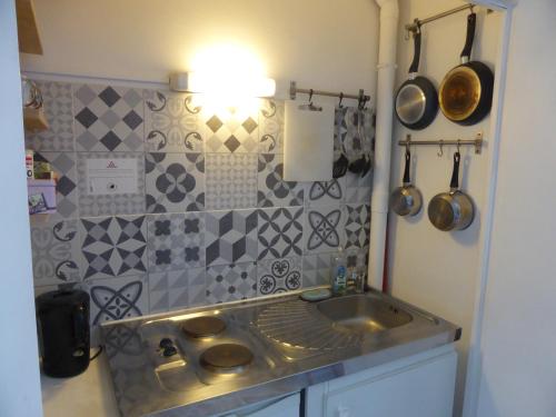 eine Küche mit einem Waschbecken und einer gefliesten Wand in der Unterkunft Studio calme au coeur de Tours in Tours