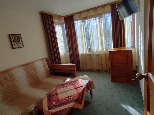 Habitación con sofá, mesa y ventanas. en Guest Rooms Grachenovi en Bansko