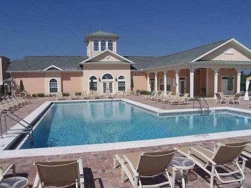 a large swimming pool with chairs and a building at Apartment Kissimmee - Orlando in Kissimmee