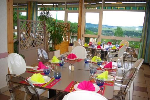 une salle à manger avec tables, chaises et fenêtres dans l'établissement VVF Montpeyroux Auvergne, à Parent