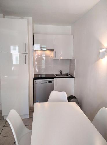 - une cuisine avec une table et des chaises blanches dans la chambre dans l'établissement Résidence Graziella Studio 201, à Juan-les-Pins