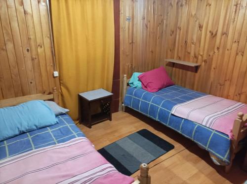 two beds in a room with wooden walls at Residencial familiar in Puerto Montt