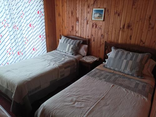 2 Betten in einem Zimmer mit holzgetäfelten Wänden in der Unterkunft Residencial familiar in Puerto Montt