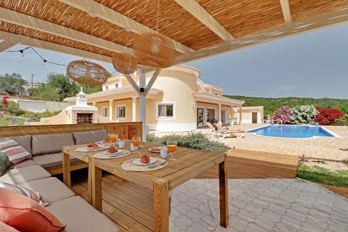 une terrasse avec une table et une piscine dans l'établissement Casa do Pomar by Portucasa, à Alte