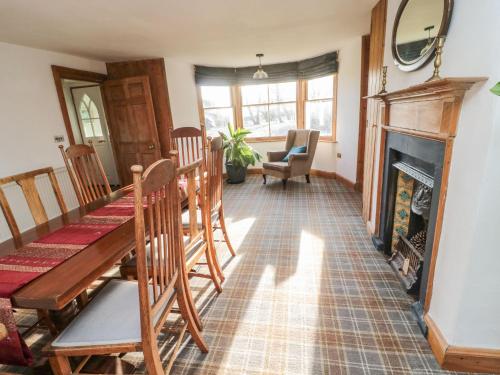 a dining room with a table and a fireplace at The Coach House in Cornhill-on-tweed