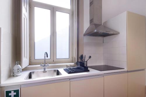 eine Küche mit einem Waschbecken und einem Fenster in der Unterkunft Crooked Floor House - 1st floor in Porto