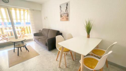un salon avec une table, des chaises et un canapé dans l'établissement Le Magali, à Villeneuve-Loubet