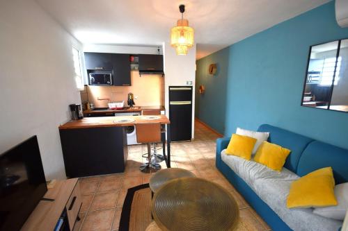 a living room with a blue couch and a kitchen at La bulle bleue - Coeur de St Gilles les bains in Filaos