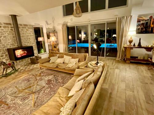 a living room with a couch and a tv at Maison d'Hôtes de Charme Le Clos de la Fontaine Piscine & SPA in Labastide-Marnhac