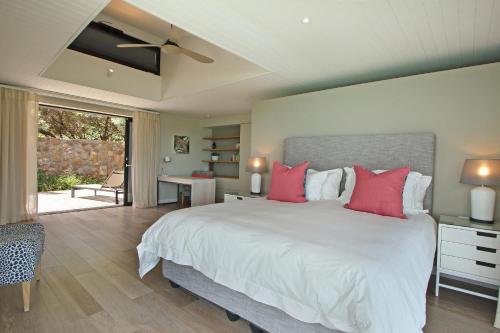 a bedroom with a large white bed with red pillows at Villa Frangipani in Cape Town