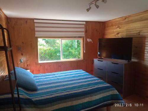 1 dormitorio con 1 cama y TV de pantalla plana en Azul y Verde B&B en Ancud