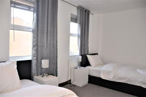 1 dormitorio con 2 camas y ventana en London Zone 2, 2 Bedroom House, en Londres