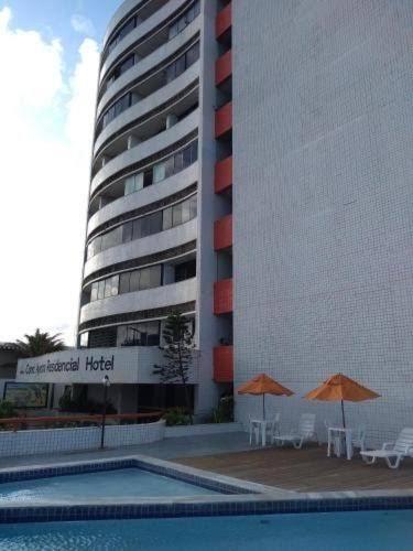 un hotel con piscina, 2 sombrillas y un edificio en FLAT COM VISTA PARA O MAR - Cond Ayambra Residencial, en Natal