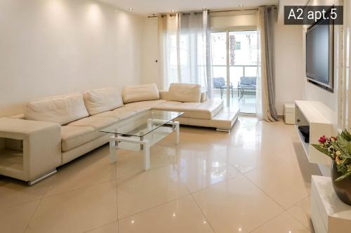 a living room with a white couch and a glass table at Palmore Resort apartments in Eilat