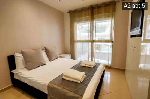 a bedroom with a bed with white sheets and a window at Palmore Resort apartments in Eilat