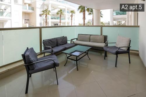 a balcony with a couch and chairs and a table at Palmore Resort apartments in Eilat