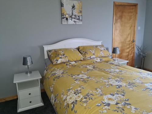 a bed with a yellow comforter with flowers on it at Mackenzie 25 in Stornoway