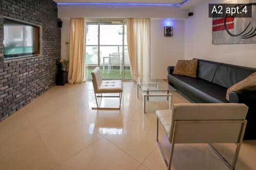 a living room with a black couch and chairs at Palmore Resort apartments in Eilat