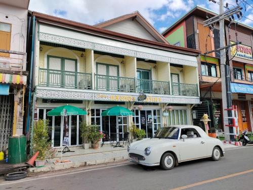 Sangthong Heritage hotel โรงแรมแสงทองเฮอริเทจ في That Phanom: سيارة بيضاء متوقفة أمام مبنى