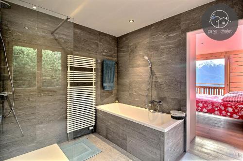 een badkamer met een bad en een slaapkamer bij L'Eden in Ovronnaz