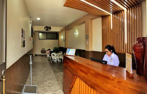a woman sitting at a reception desk in a lobby at Studio 69 Aparthotel in Iquitos