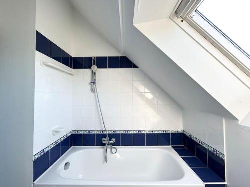 a bath tub in a bathroom with blue tiles at Grand Appartement duplex vue mer in Fouesnant