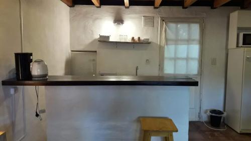 a kitchen with a counter and a wooden stool at COMPLEJO DRUMMOND en el Camino del Vino in Ciudad Lujan de Cuyo