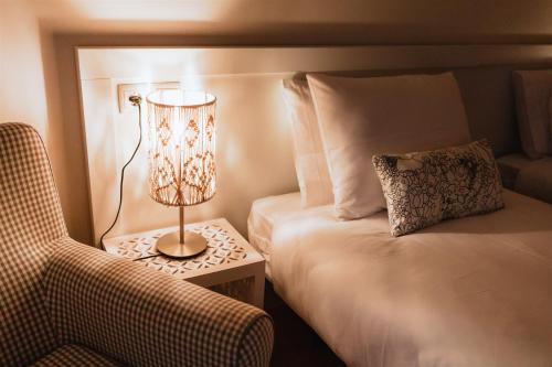 a hotel room with a bed and a lamp and a chair at Sunshine Beach Apartment in Leiria