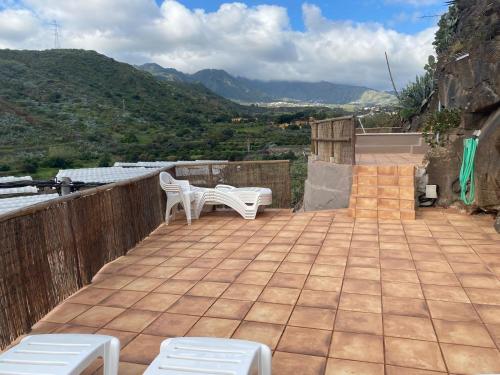 a patio with two white chairs and a table at Villa Cueva en la naturaleza, Tecen, Valsequillo in Valsequillo