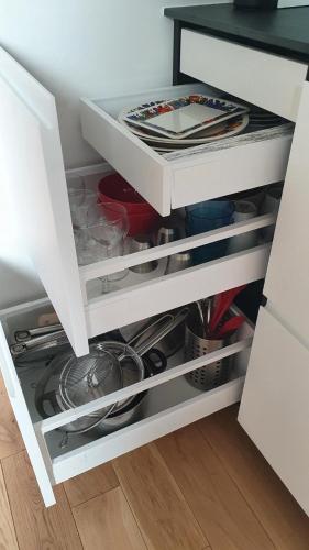 a drawer in a white cabinet filled with dishes at Chambre d'hôtes confort et charme Paris 9eme in Paris