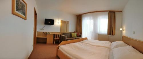 a bedroom with a bed and a living room at Hotel Gästehaus Neubauer in Kaltenberg