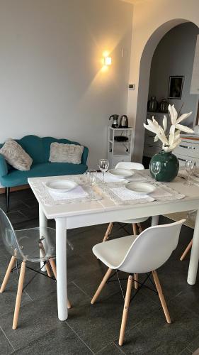 un tavolo da pranzo bianco con sedie e un divano di Villa Nogara a Menaggio