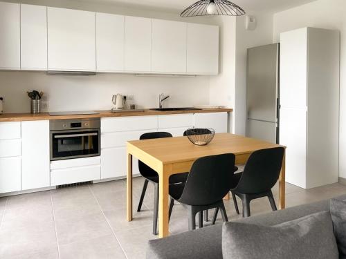 une cuisine avec des armoires blanches et une table et des chaises en bois dans l'établissement Capucins 2 chambres 400 m du centre ville, à Annecy