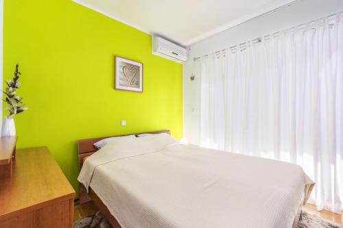sypialnia z zieloną ścianą z łóżkiem i biurkiem w obiekcie Apartment Carigo w mieście Karigador