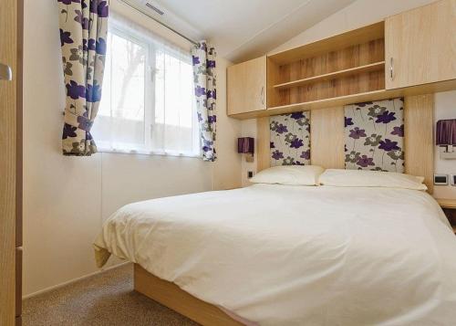 Un dormitorio con una gran cama blanca y una ventana en Seadown Park, en Charmouth