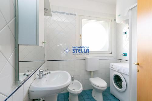 a bathroom with a sink and a toilet and a window at Condominio Vittorio in Lido di Jesolo