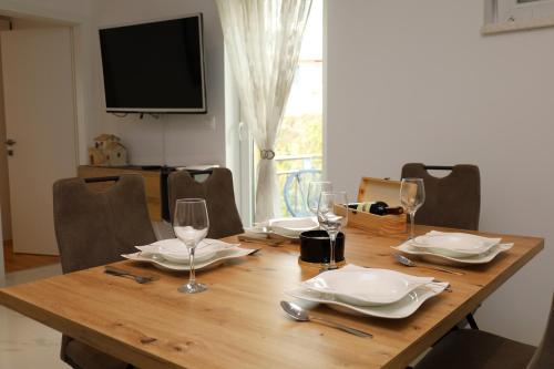 a wooden table with plates and wine glasses on it at Dalmata D in Podstrana