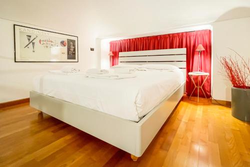 un grande letto bianco in una stanza con una tenda rossa di LuxRent Loft Lagrange a Torino