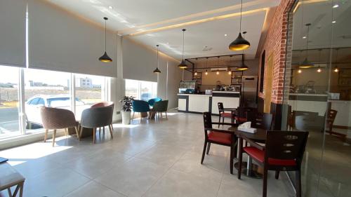 a dining room with tables and chairs and a kitchen at Sama Muscat Hotel in Al Khawḑ