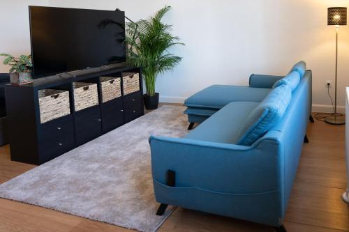 uma sala de estar com um sofá azul e uma televisão em Central Szeged Apartment em Szeged