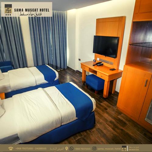 a hotel room with two beds and a desk with a television at Sama Muscat Hotel in Al Khawḑ