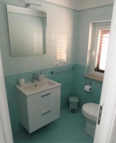 a bathroom with a sink and a toilet and a mirror at CASA VIA ALVARO in Roccella Ionica