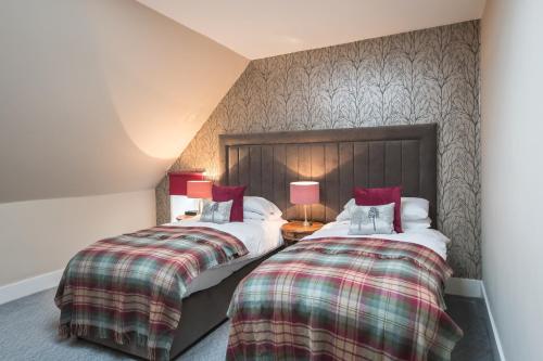 two beds sitting next to each other in a room at Rossie Ochil House with Hot Tub in Forgandenny
