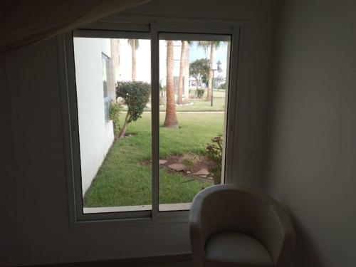 una ventana con una silla que da a un patio en Appartement ola blanca, en Sidi Rahal