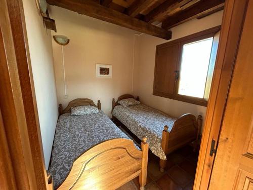2 Betten in einem kleinen Zimmer mit Fenster in der Unterkunft Casa Rural Ocre in Avila