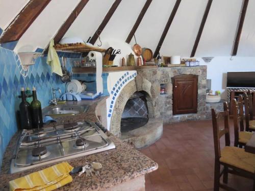 a kitchen with a stove and a stone fireplace at Casa in campagna in Dorgali