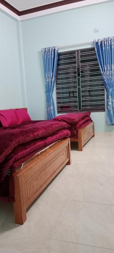 1 dormitorio con 2 camas y una ventana con cortinas azules en Nhà Nghỉ Tấn Phúc en Thôn Phước Sơn