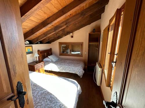 Un dormitorio con dos camas en una habitación con techos de madera. en Casa Rural Naranja, en El Tiemblo