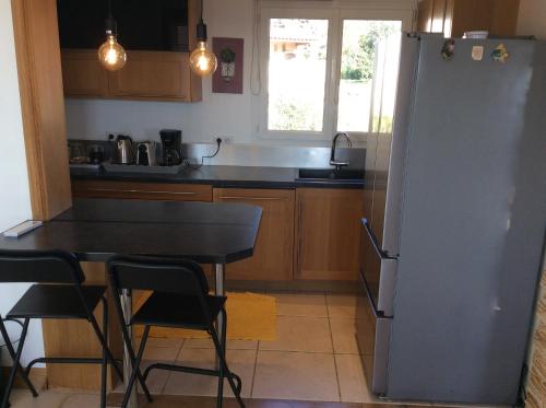 a kitchen with a refrigerator and a table and chairs at Hauts de st pierre 3 chambres belle terrasse climatisation in Fayence